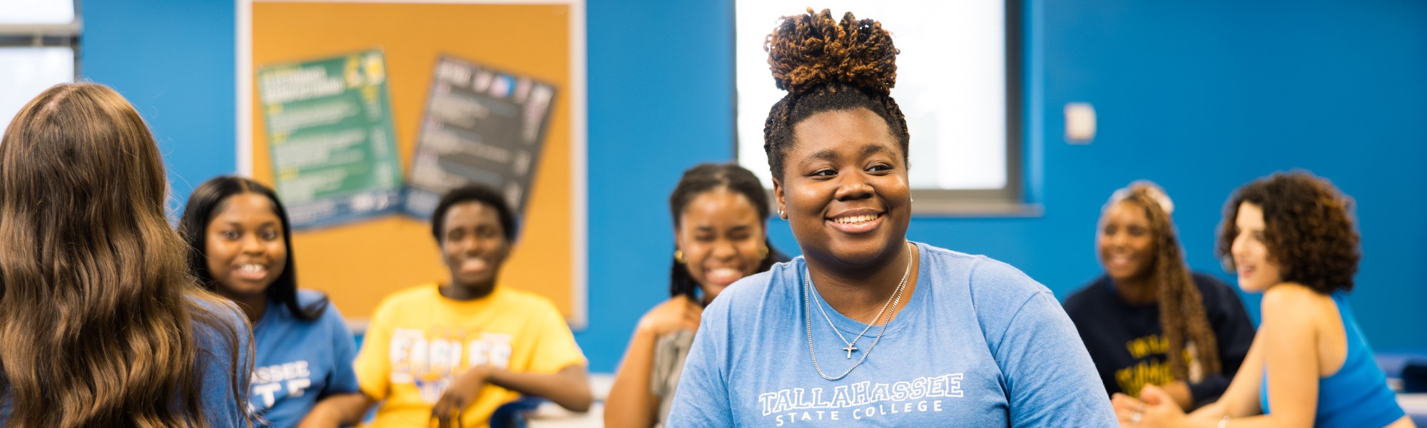 Students sitting in class together chatting and smiling.